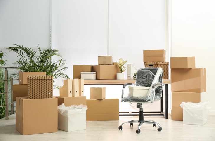 A partially packed office with boxes and an office chair wrapped in plastic.
