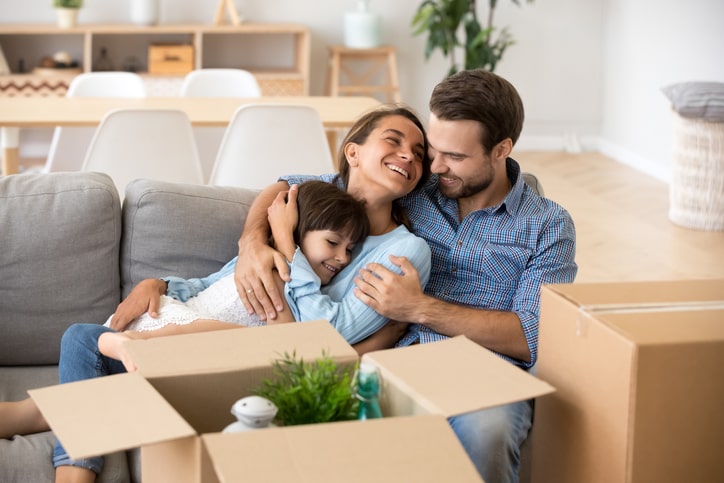 A smiling family hugging after packing boxes for a move.