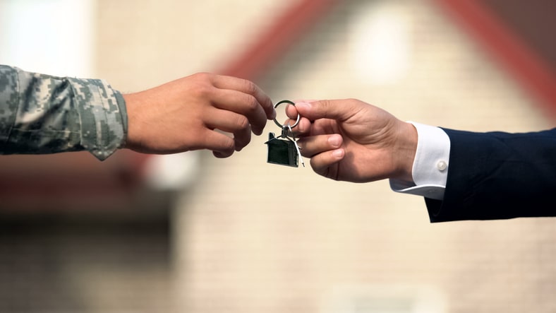 A realtor handing keys for a house to a military service member.