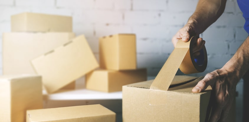 A man taping a box shut for storage.