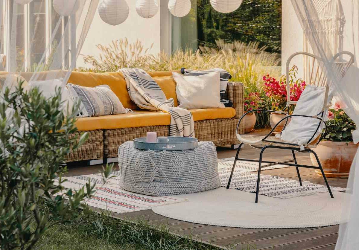 A chair, footrest, and couch sit on an outdoor patio