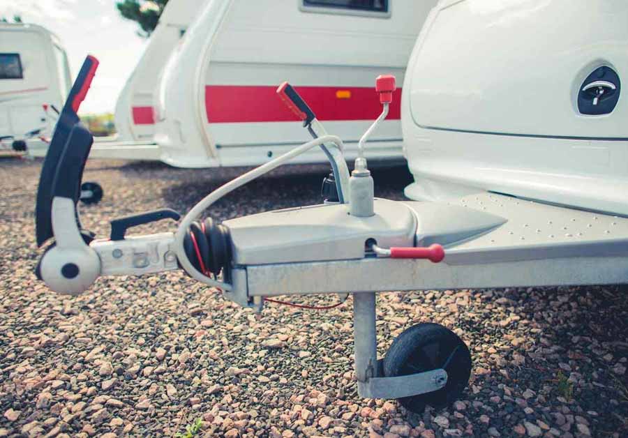 An RV sits parked in a storage lot next to other small RVs