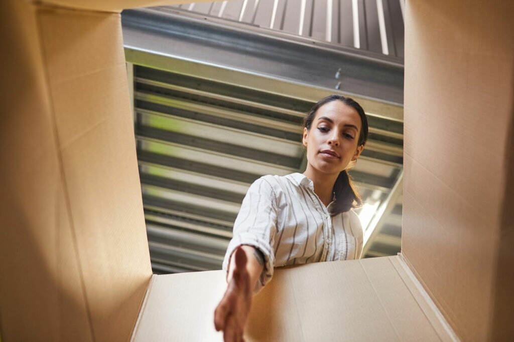 A woman reaches into a cardboard box 