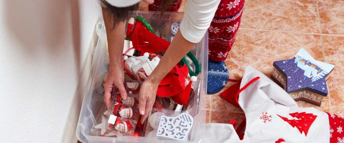 A person sits on the ground sorting through a box of holiday decorations