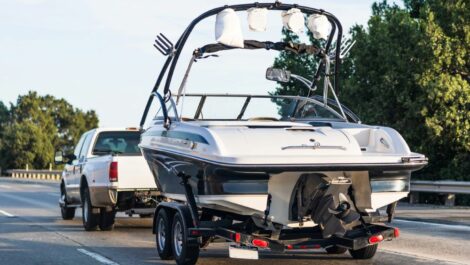 A pickup truck tows a boat on a trailer down the highway.