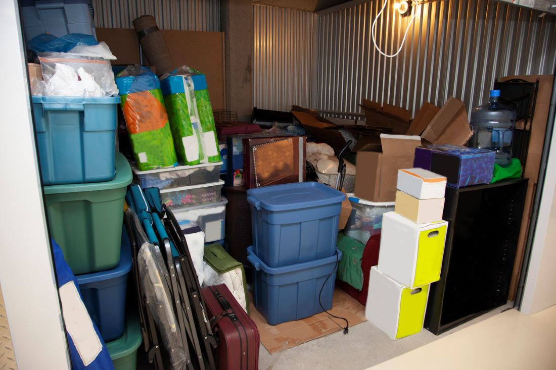 A storage unit filled with tubs, boxes, and various clutter.