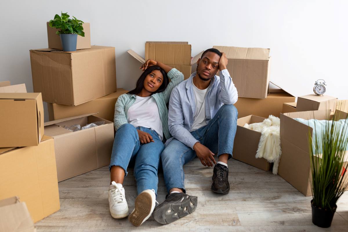 A couple sitting in their living room stressed with moving boxes