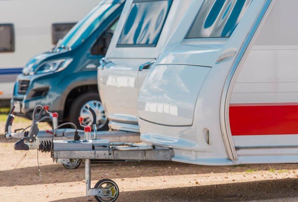 Three different sized recreation vehicles lined up in a storage lot