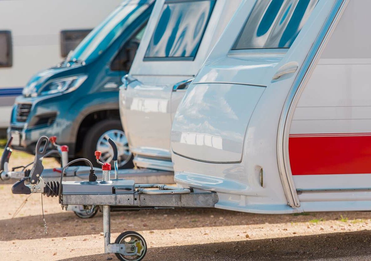 Three different sized recreation vehicles lined up in a storage lot