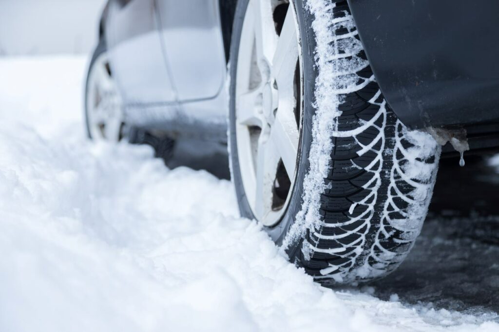 A car tire driving through a snowy road