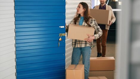 Young woman and man with big cardboard boxes into warehouse