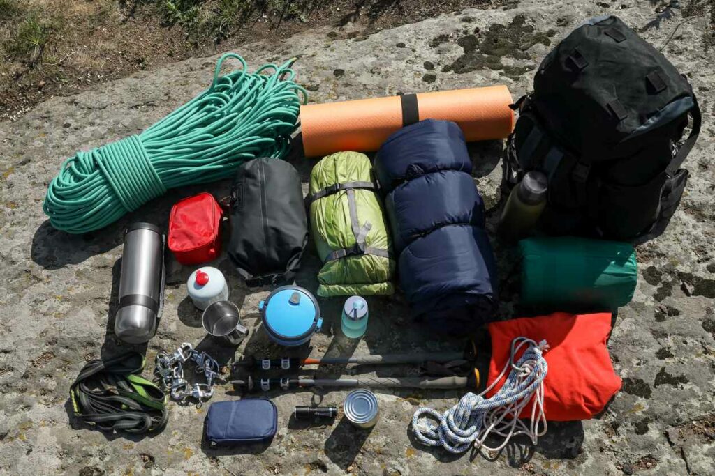 A full set of camping gear complete with bottles, rope, sleeping bags, and a tent.
