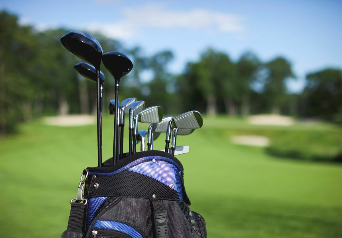 A golf bag and clubs against a defocused green background.