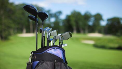 A golf bag and clubs against a defocused green background.