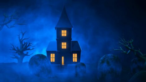 Blue concept image of a haunted house with a graveyard in the foreground.