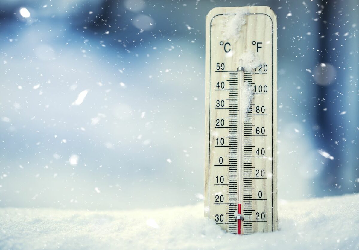 A thermometer drops to below-freezing temperatures in a pile of snow.