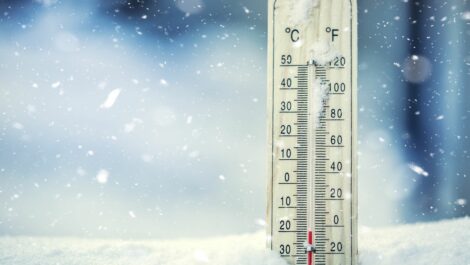 A thermometer drops to below-freezing temperatures in a pile of snow.