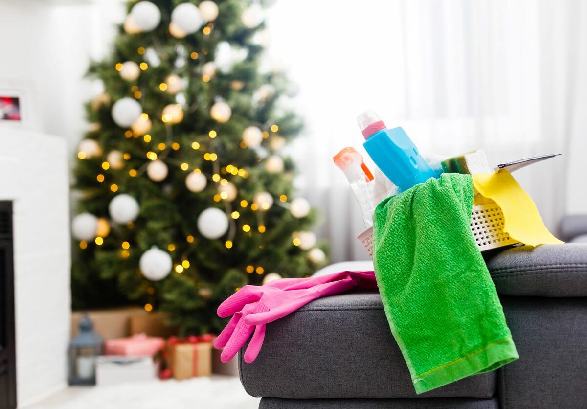 A bucket of cleaning supplies sits on a couch by a Christmas tree.