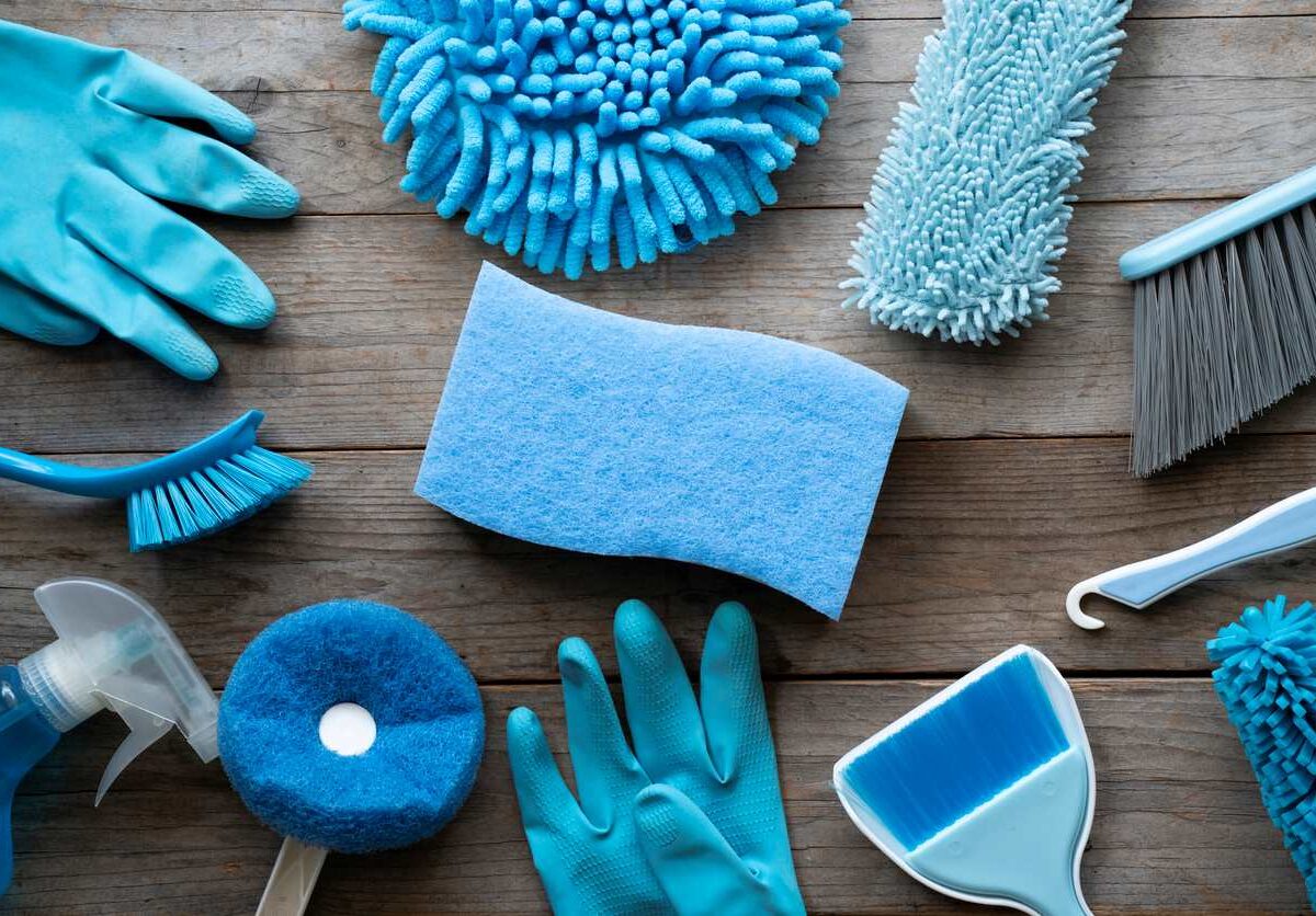 A collection of blue and teal cleaning supplies on a wooden table.
