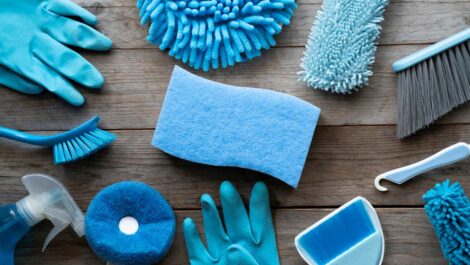 A collection of blue and teal cleaning supplies on a wooden table.