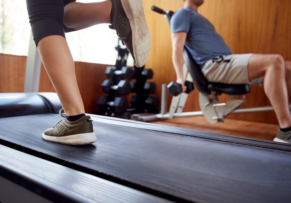 A running woman and a man lifting weights working out together