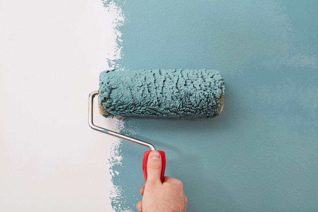 Someone painting a white wall blue