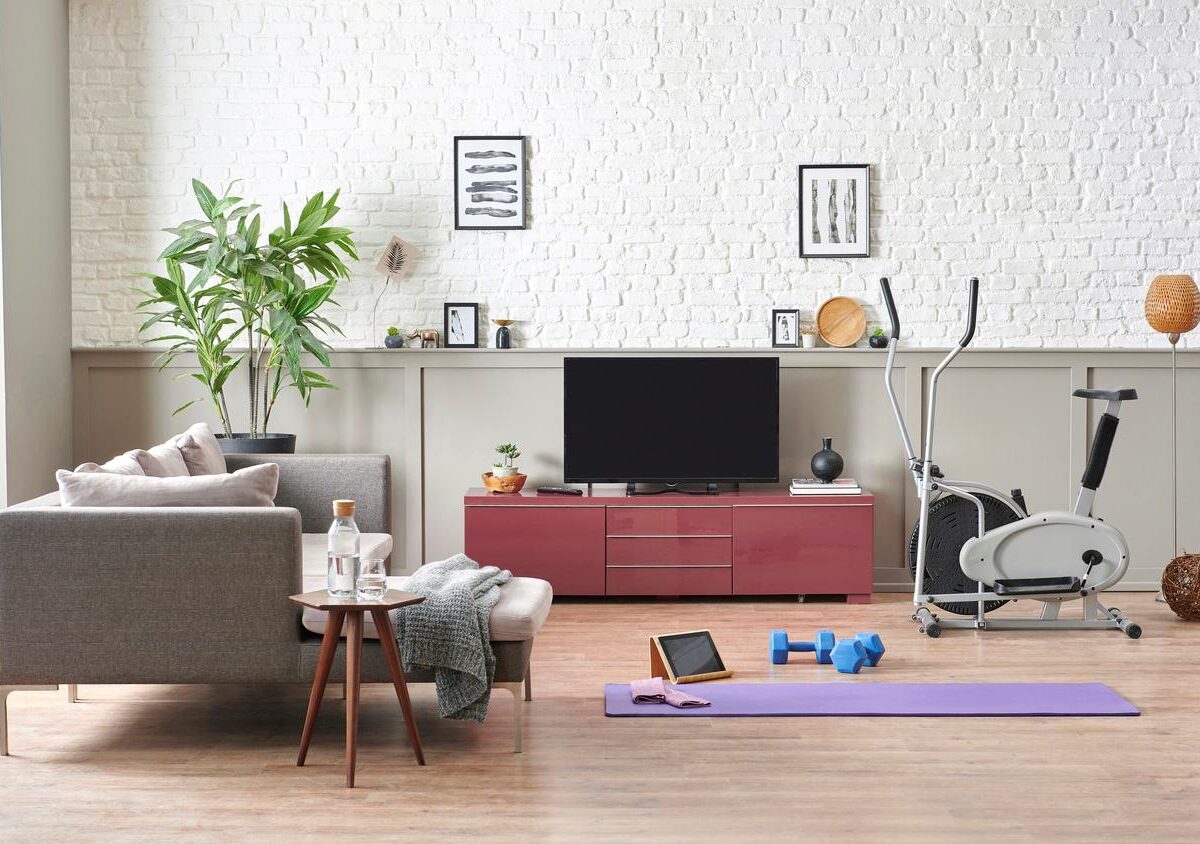 An in-home gym set up with a yoga mat, free weights, and gym equipment