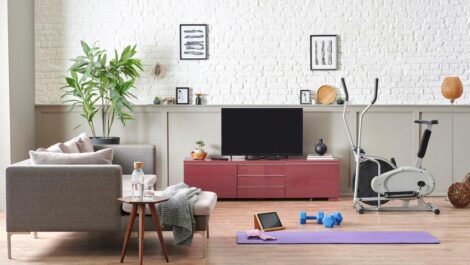 An in-home gym set up with a yoga mat, free weights, and gym equipment