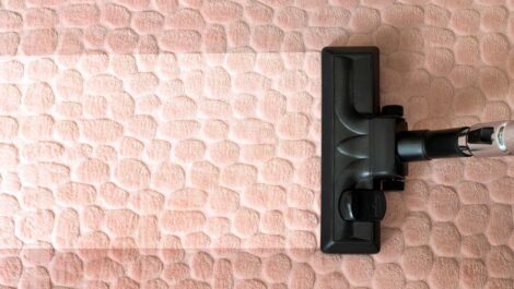 A vacuum cleans dirt from a tan-colored rug.
