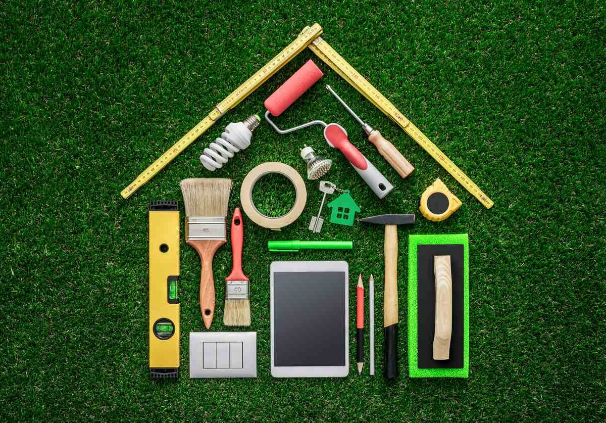 A bundle of tools in the shape of a house on grass